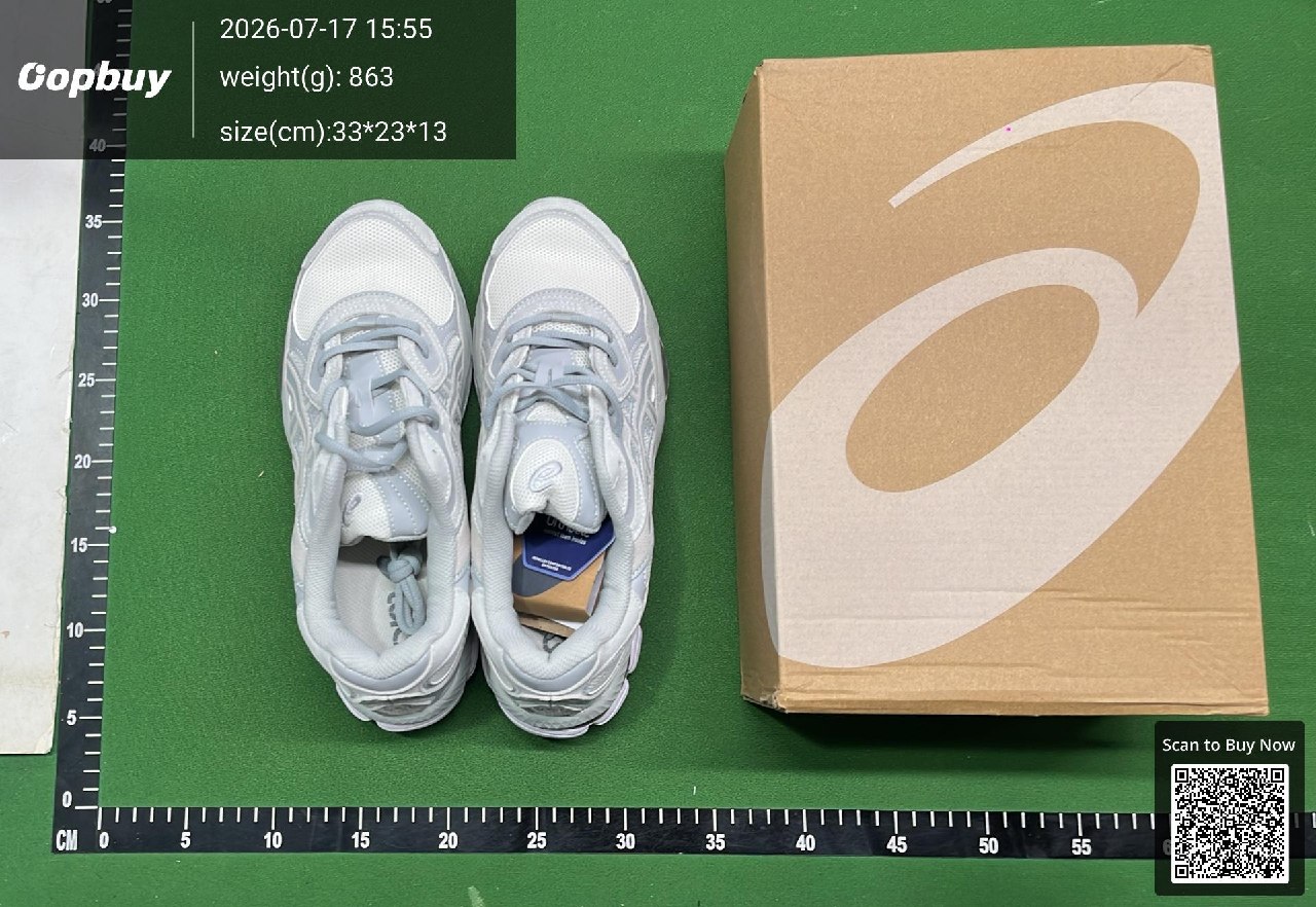 A pair of pale trainers and its box on a green warehouse measuring mat